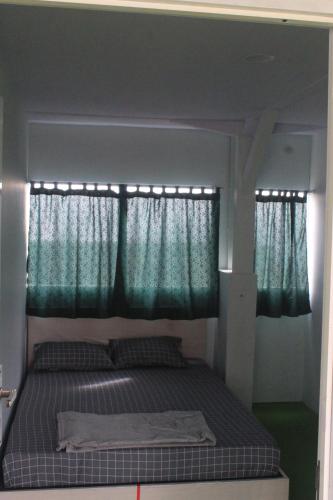 a bed in a small room with green curtains at Wong Pai Ton Villa in Ngadisari