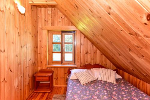 ein Schlafzimmer mit einem Bett in einer Holzhütte in der Unterkunft Stirnelės viensėdis in Stirniai