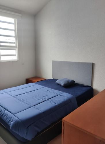 a bedroom with a blue bed and a window at Cozy House with Private Garden in Pachuca in Pachuca de Soto