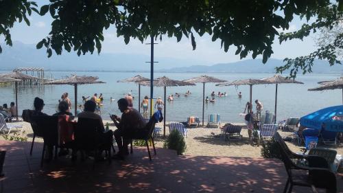 a group of people sitting at a beach with umbrellas at Apartmani Alex Beach in Star Dojran