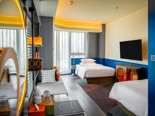 a hotel room with two beds and a flat screen tv at Hotel Indigo Zhuhai Xiangzhou by IHG in Zhuhai