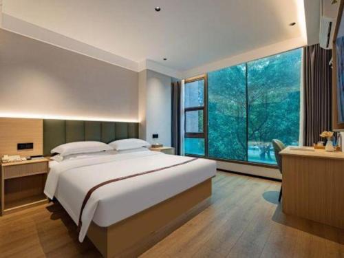 ein Schlafzimmer mit einem großen Bett und einem großen Fenster in der Unterkunft GreenTree Inn Jiaxing ZhongHuan South Road Zhonggang City Express Hotel in Jiaxing