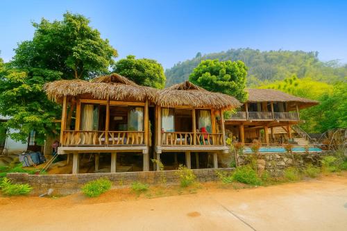ein großes Holzhaus mit Strohdach in der Unterkunft Mường Hịch Homestay in Mai Châu