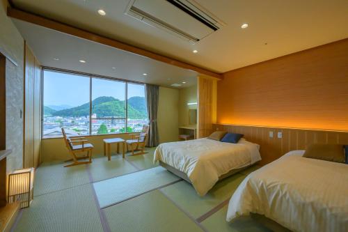 een slaapkamer met twee bedden en een groot raam bij Tendo Hotel in Tendo