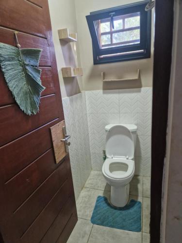 a bathroom with a toilet with a door and a window at Villa Tahina in Ramena