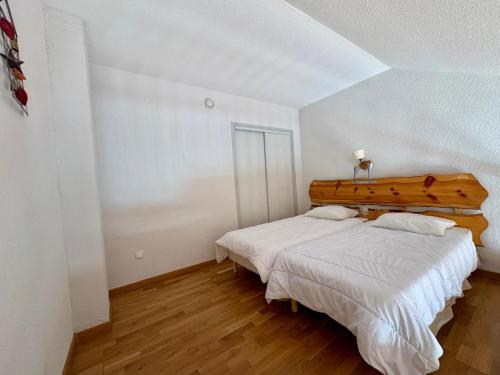 a bedroom with a large bed with a wooden headboard at Appartement cosy T2 Duplex in Bolquere Pyrenees 2000
