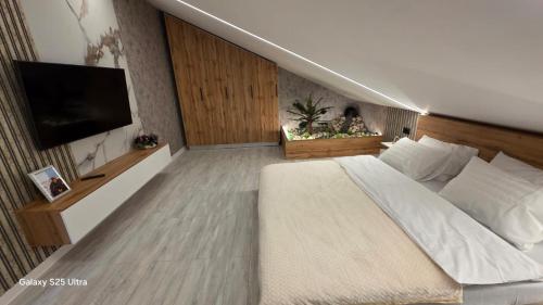 Un dormitorio con una cama grande y un televisor de pantalla plana. en Cazare Văleanca Lux, 