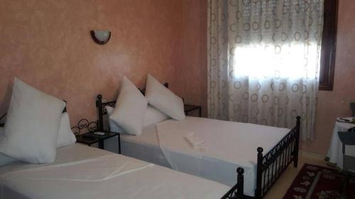 a bedroom with two beds with white pillows and a window at Hotel Espace Tifawine in Tafraoute