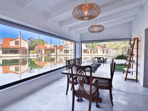 a dining room with a table and chairs and large windows at Manhattan Estates - Plettenberg Bay in Plettenberg Bay
