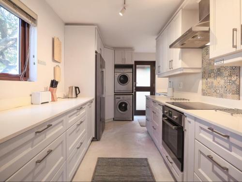 a kitchen with white cabinets and a washer and dryer at Manhattan Estates - Plettenberg Bay in Plettenberg Bay