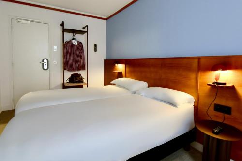 Agate Hôtel في باريس: غرفة نوم بسرير أبيض كبير مع لوح رأس خشبي