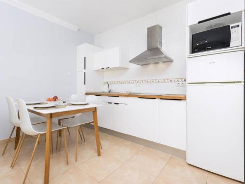 a white kitchen with a wooden table and white appliances at My little paradise in Cotillo
