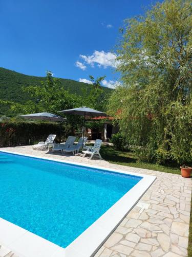 una piscina con dos sillas y sombrillas en Holiday Home Vemini, en Mostar