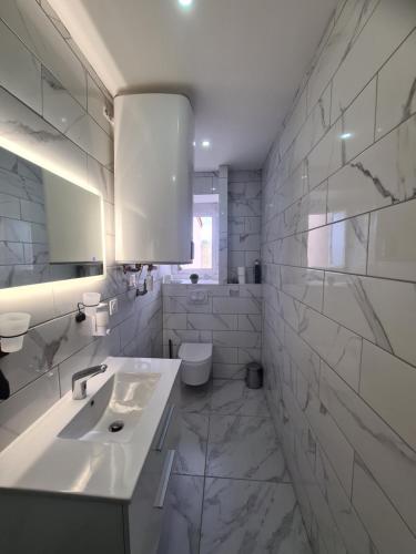 a white bathroom with a sink and a toilet at Rive gauche Rive droite 2 Appartements côte à côte neufs et bien équipés in Le Creusot