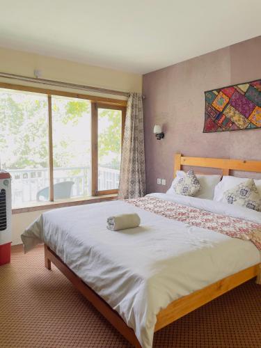 a bedroom with a large bed with a large window at White Apricot Lodge in Baltit