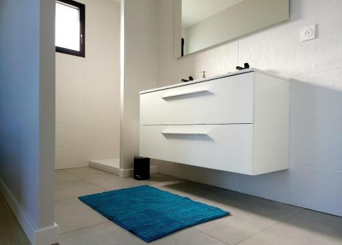 een badkamer met een witte wastafel en een blauw tapijt bij Villa Ty Billou in Santec