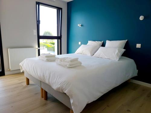 een slaapkamer met een groot wit bed met blauwe muren bij Villa Ty Billou in Santec