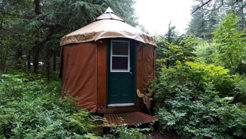 a yurt with a green door in a forest at Nauti Otter Inn and Yurt Village in Bear Creek