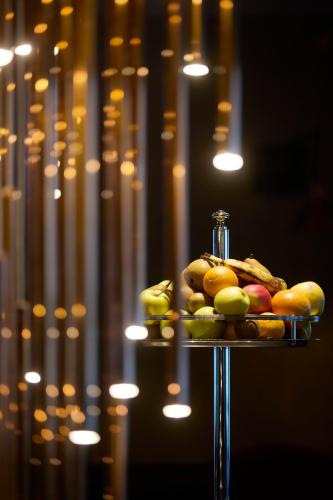 Un plato de fruta en un soporte con una botella. en Hôtel Taj-I Mah by Les Etincelles, en Arc 2000