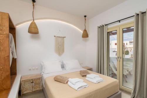 Un dormitorio blanco con una cama con toallas. en Vive Mare Milos, en Pachaina