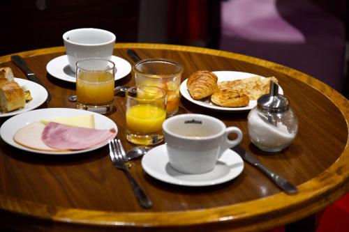 Una mesa de madera con platos de comida y bebidas para el desayuno. en Agate Hôtel, en París
