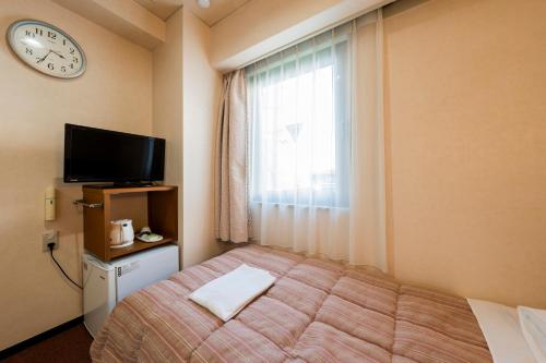 a bedroom with a bed and a window with a clock at 南部ホテル in Kitakami