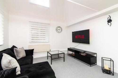 a living room with a black couch and a tv at Bright 3 Bed Ground Floor Flat - Derby in Derby