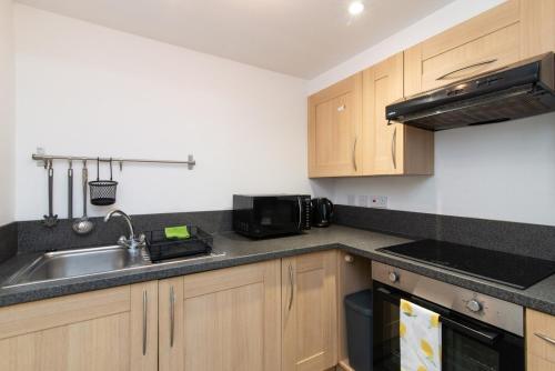 a kitchen with a sink and a microwave at Bright 3 Bed Ground Floor Flat - Derby in Derby