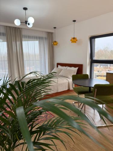 ein Schlafzimmer mit einem Bett, einem Tisch und einer Pflanze in der Unterkunft Apartament 13 Zegrze - Rezydencja Zegrze in Zegrze