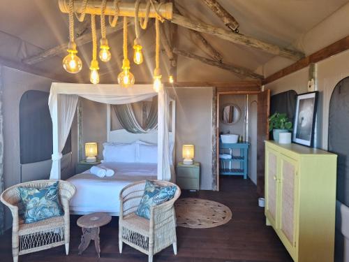 a bedroom with a canopy bed and two chairs at Trekosglamping luxury tents 