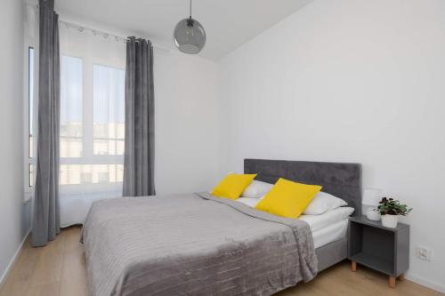 a white bedroom with a bed with yellow pillows at Warsaw Elegant Apartment with Parking and Balcony by Noclegi Renters in Warszawa