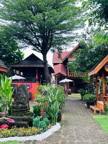 a garden with flowers and a tree and a building at Thai Tom s GuestHouse in Chiang Mai