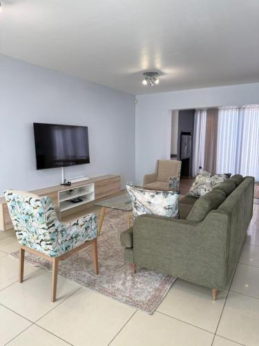 a living room with a couch and chairs and a tv at Haven Luxury Apartment in Windhoek