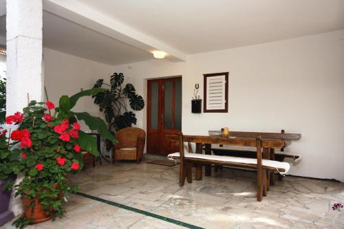 une chambre avec un banc, une table et des fleurs dans l'établissement Double Room Banjol 5077a, à Rab