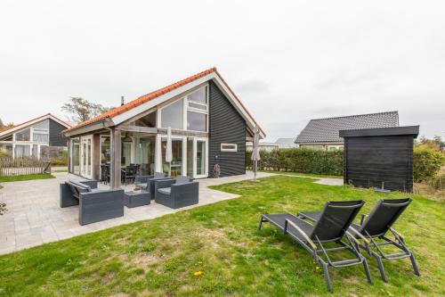 Un patio trasero con sillas y una casa en Zonnedorp 26 Renesse: Comfortabele Strandvakantie aan de Noordzee, en Renesse