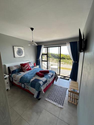 een slaapkamer met een bed en een groot raam bij Seebossie in Struisbaai