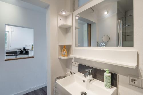 ein weißes Badezimmer mit Waschbecken und Spiegel in der Unterkunft 1-Zimmerapartment Am Hochwald in Bad Liebenzell