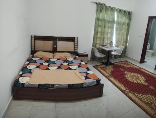 a bedroom with a bed and a table and chairs at Raha Hostel in Ḩayl Āl ‘Umayr
