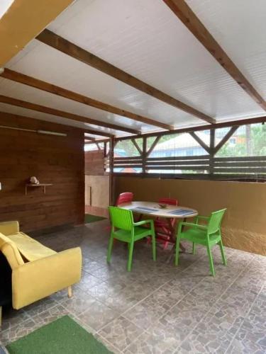 a dining room with green chairs and a table at Appartement avec piscine à Capesterre-Belle-Eau in Capesterre-Belle-Eau