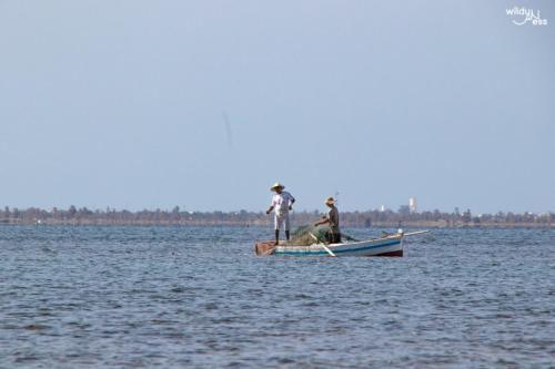 two men are standing on a boat in the water at trip to djerba in Djerba