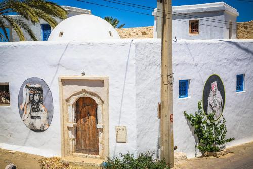 a white building with a door and a painting of a skull at trip to djerba in Djerba