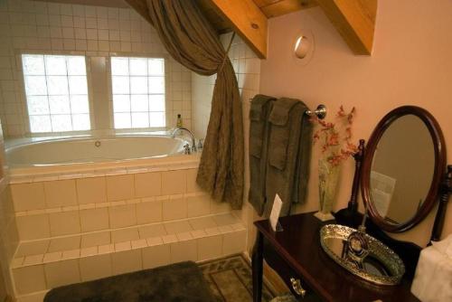 ein Badezimmer mit Badewanne, Waschbecken und Spiegel in der Unterkunft Family Cabin Vacation Getaway with Waterfall Views in Northwest Arkansas in Ponca