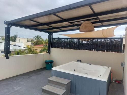 a bath tub on a balcony with a surfboard at So Chic Family Villa in Flic-en-Flac