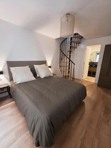 Charmant Duplex في إسوار: سرير كبير في غرفة بها درج حلزوني