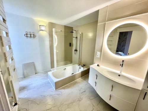 ein weißes Badezimmer mit einer Wanne, einem Waschbecken und einer Badewanne in der Unterkunft La Villa au Bosquet in Belleville-sur-Vie