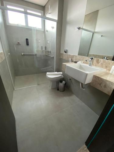 a bathroom with a sink and a shower and a toilet at Uberlândia Suítes Hotel in Uberlândia
