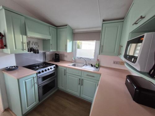 een keuken met groene kasten, een fornuis en een wastafel bij Lodge Priscilla in Eext