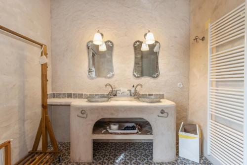une salle de bain avec un lavabo et deux miroirs au mur dans l'établissement La Festa Dels Sentits, Casa Rural, à Sant Martí de Maldá
