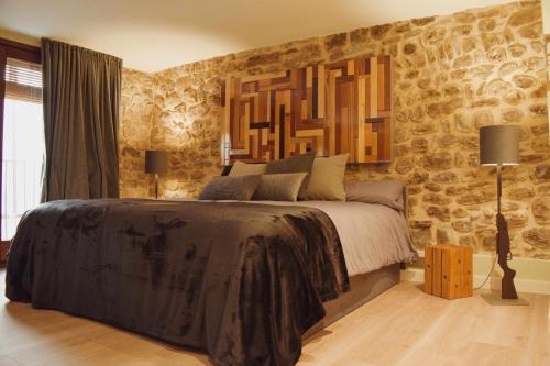 a bedroom with a large bed with a stone wall at Kel Domènech Luxury Apartment in Besalú