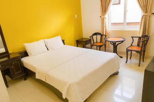 a bedroom with a large white bed and chairs at Tan Duy Hotel in Xuyên Mộc